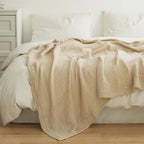 Beige cotton muslin blanket on a white bed