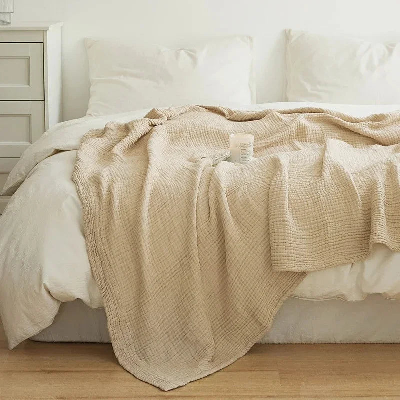 Beige cotton muslin blanket on a white bed