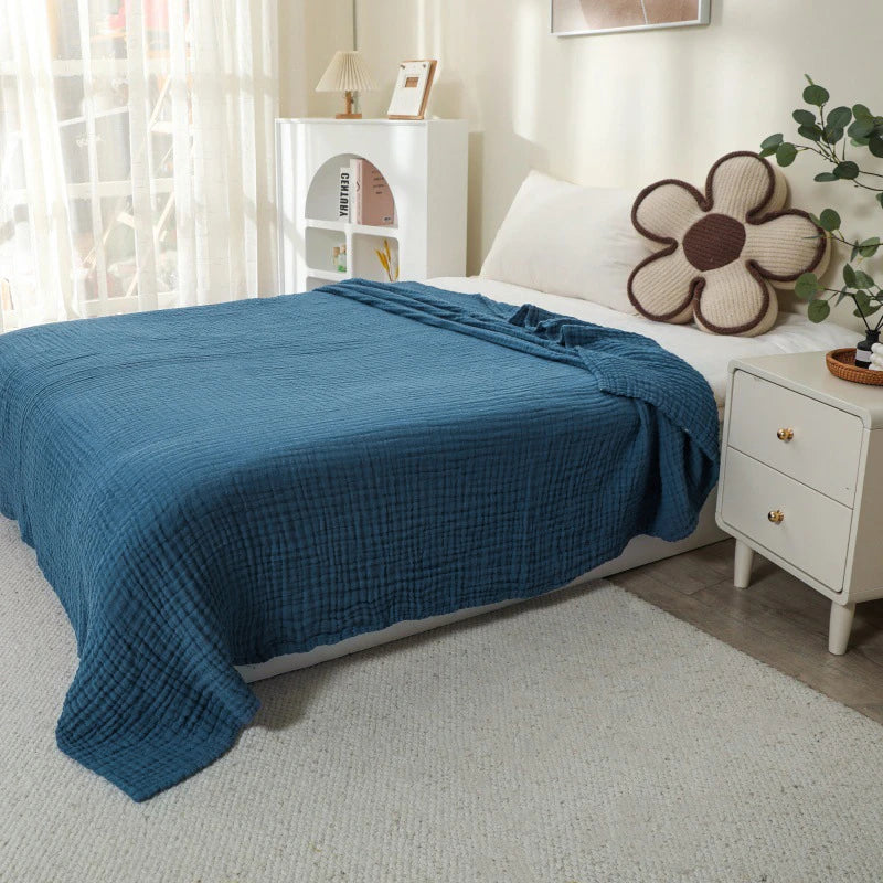 Navy blue 100% cotton muslin blanket on a bed