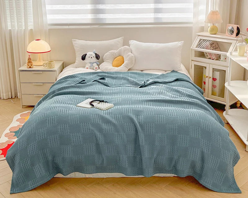 Dusty blue cotton waffle weave blanket on a bed