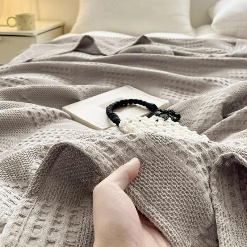Hand touching a light gray cotton waffle weave blanket