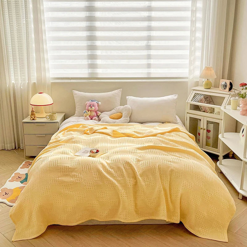 Butter yellow cotton waffle weave blanket on a bed by a window