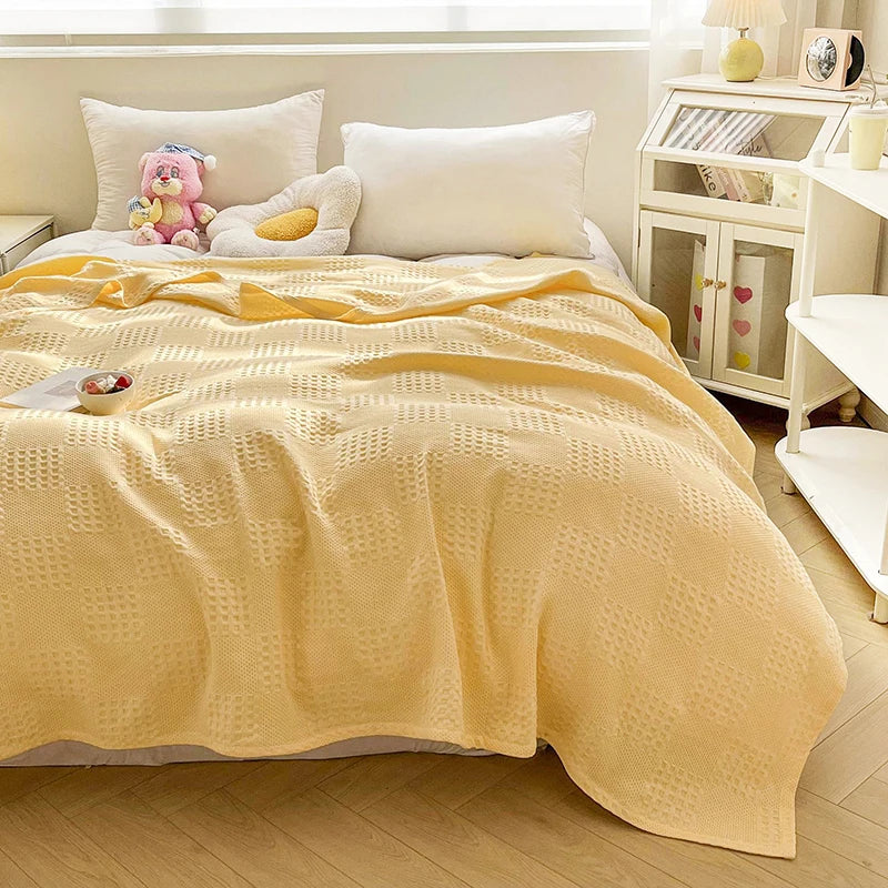 Butter yellow cotton waffle weave blanket on a bed