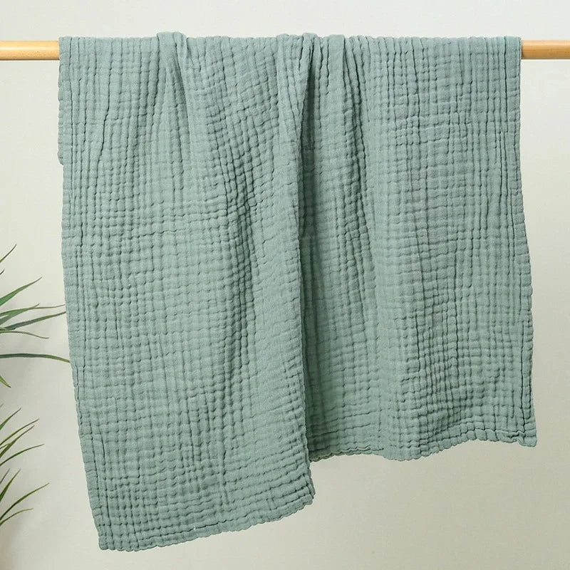 Sage green 6-layer cotton muslin throw hanging on a rail