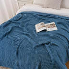 Navy blue cotton muslin blanket on a bed with a magazine