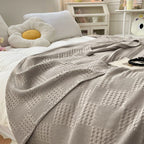 Light gray cotton waffle weave blanket on a white bed