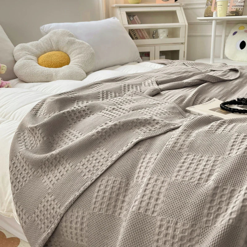 Light gray cotton waffle weave blanket on a white bed