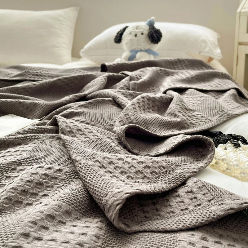Charcoal gray cotton waffle weave blanket, close-up on a bed