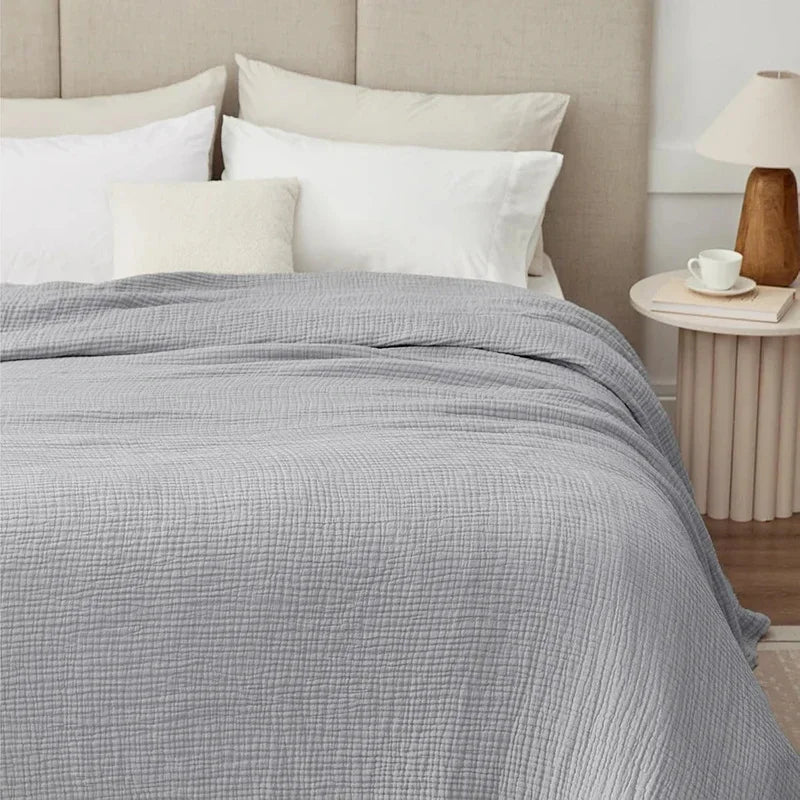 Light gray cotton muslin blanket on a bed