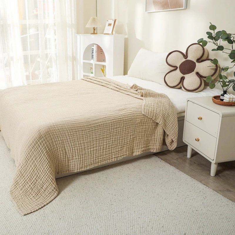 Beige 100% cotton muslin blanket on a bed