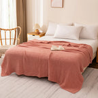 Terracotta 100% cotton muslin blanket on a bed