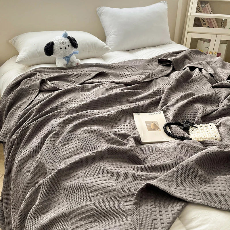Charcoal gray cotton waffle weave blanket on a bed