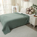 Sage green 100% cotton muslin blanket on a bed