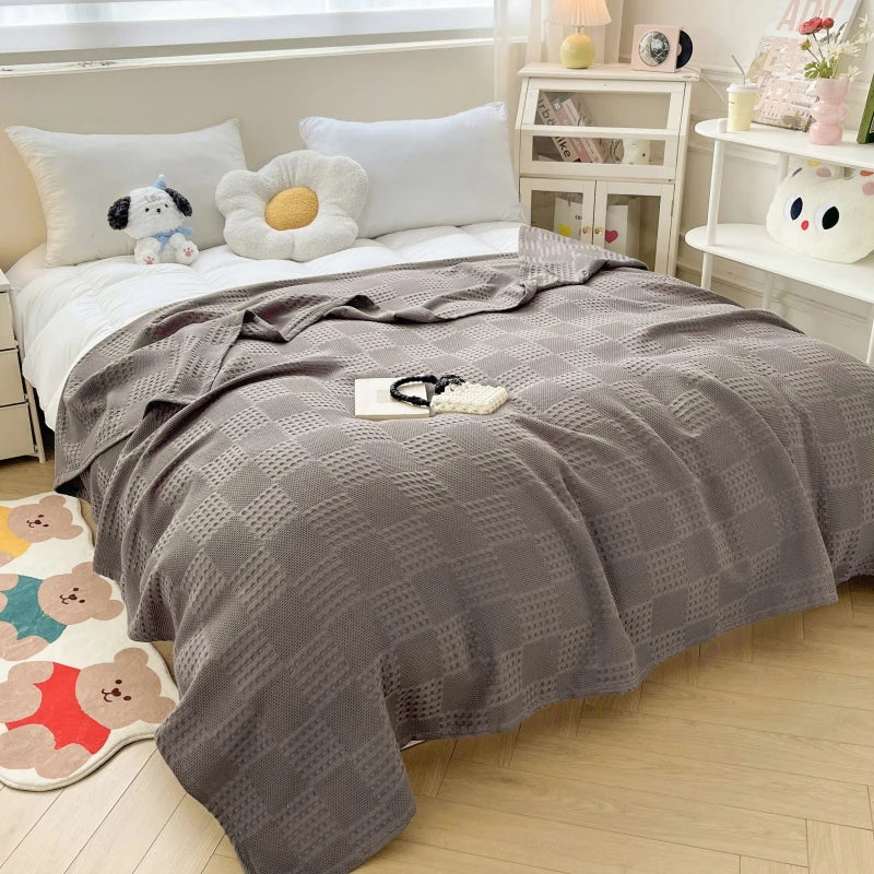 Charcoal gray cotton waffle weave blanket on a bed