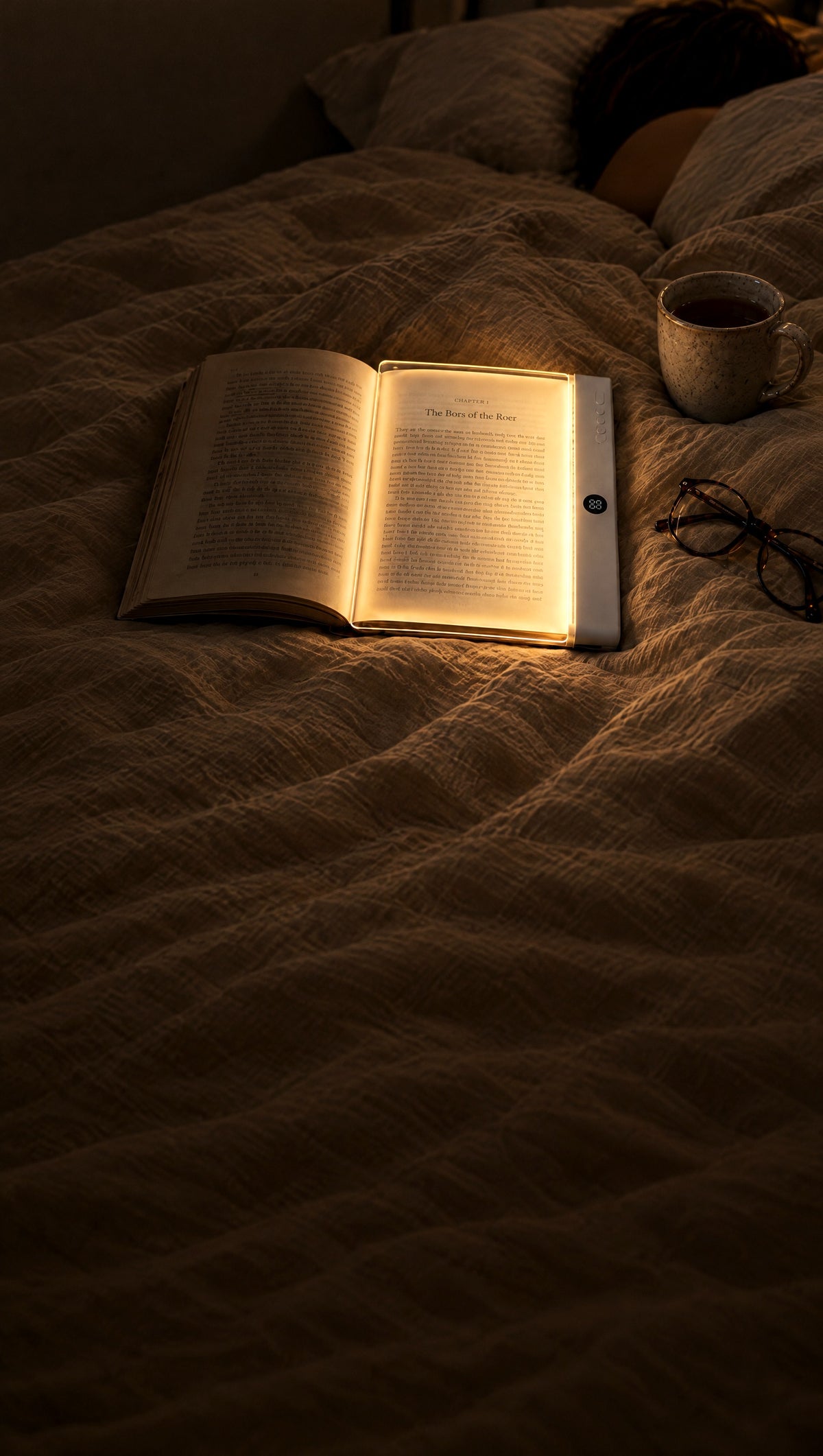 PageGlow book light glowing on one page of an open paperback in bed at night